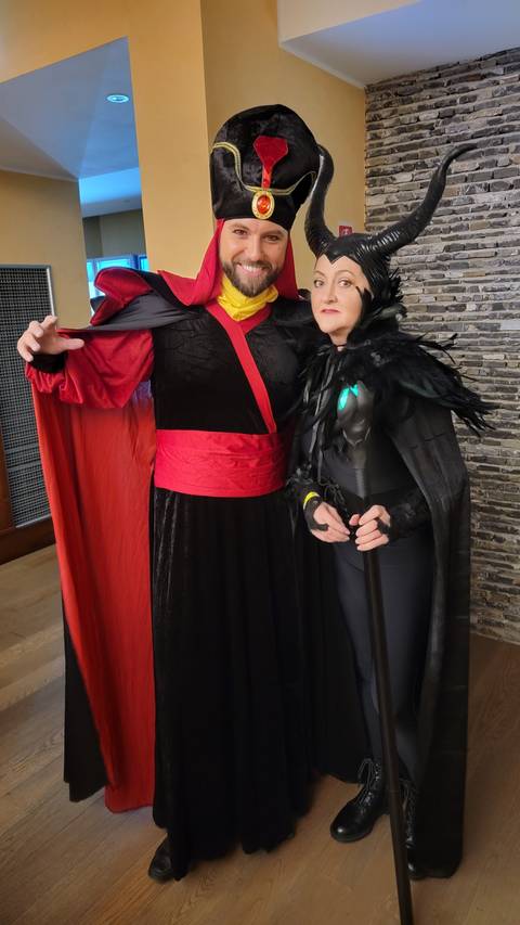 Two people in elaborate costumes posing indoors.