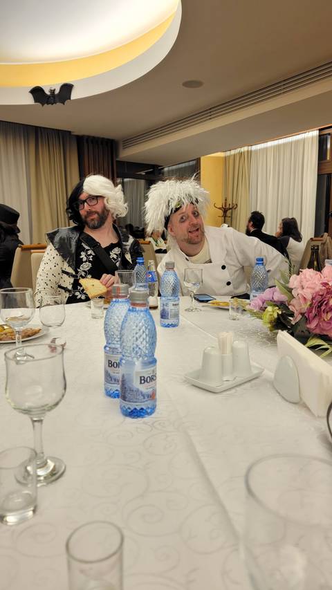 Two people dressed in costume sitting at a dining table.