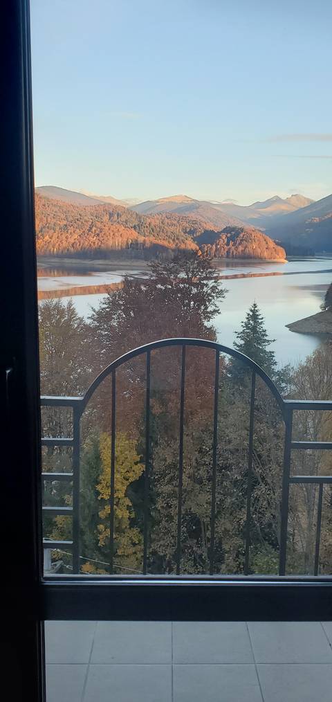       Scenic view from a balcony of a lake with mountains.
  