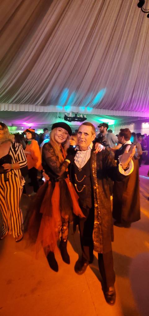 People in costumes at a night event with colorful lights.