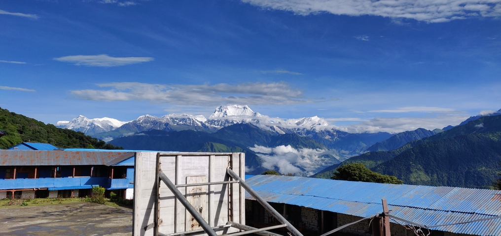       Mountain range with snow-capped peaks in the background under a clear blue sky.
  