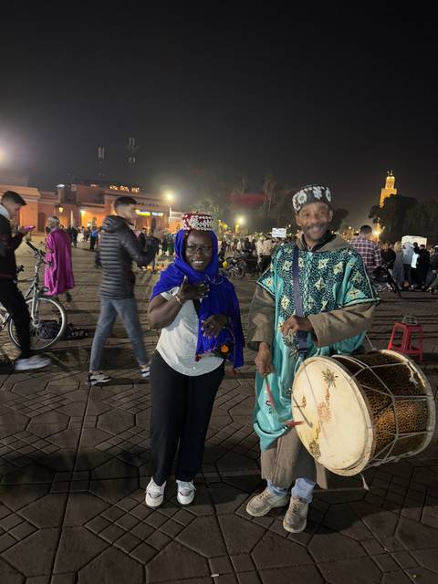 People dressed in traditional attire playing drums in a market.