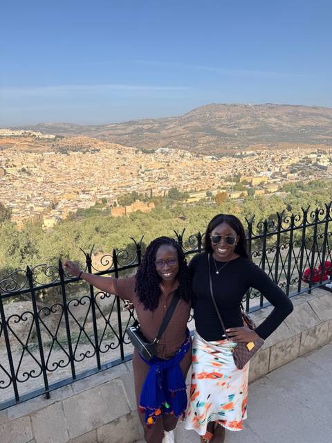       Two women in front of a cityscape view.
  