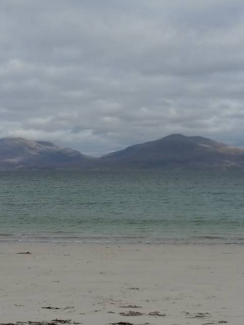A serene view of a sandy beach with distant hills.