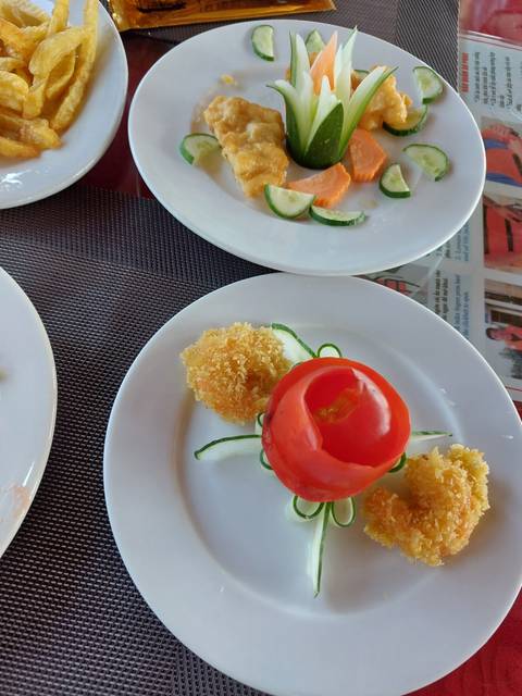 Plates with decorative food arrangement featuring a tomato and fried items.