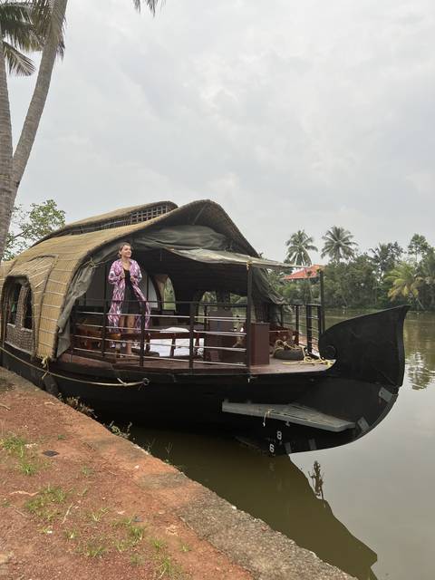 Woman standing on a houseboat by a river.