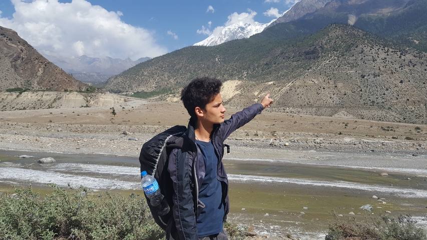       Person pointing at mountains with snowy peaks.
  