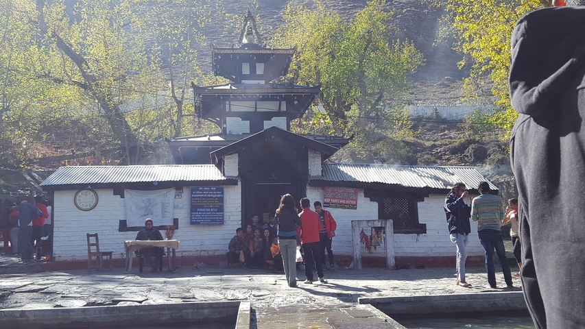       Temple with people outside under a sunny sky.
  