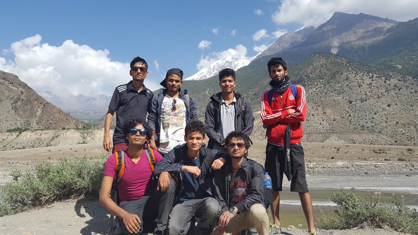       Group of people posing in front of a mountainous landscape.
  