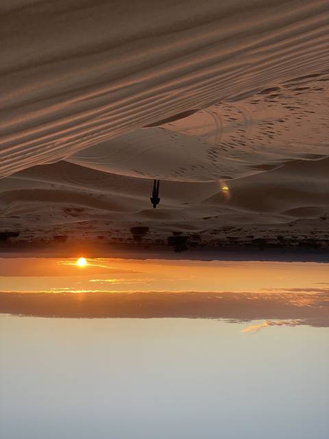 Sunset over expansive sand dunes.
