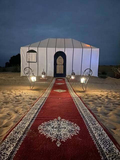      Tent entrance with a red carpet and decorative lamps.
  
