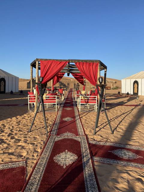 Outdoor setup with red tents and carpets on sand.