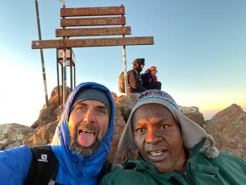 Two people posing at a mountain peak.