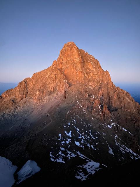 A mountain peak illuminated by the setting sun.