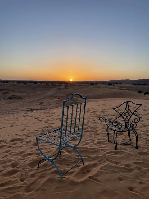       Chairs in the desert during sunset.
  