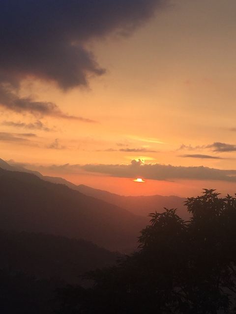 Sunset view over mountains with a partially cloudy sky.