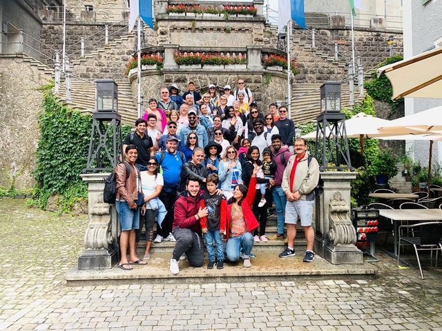 Large group photo on a set of stone steps with greenery.