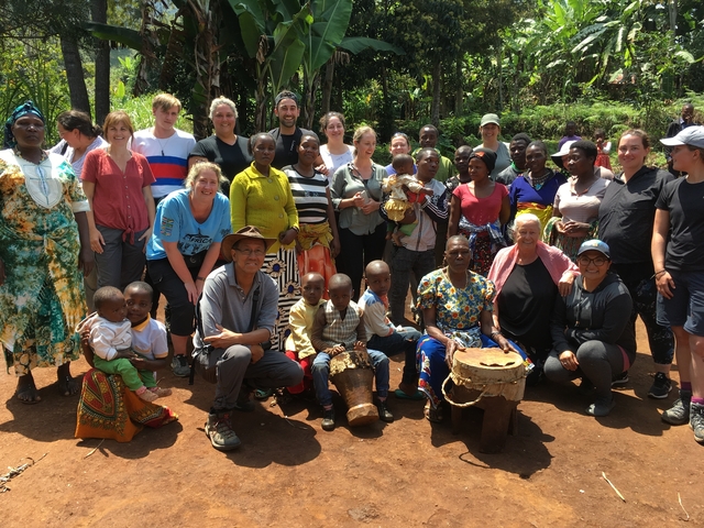 A large group of people posing outside with a local family.