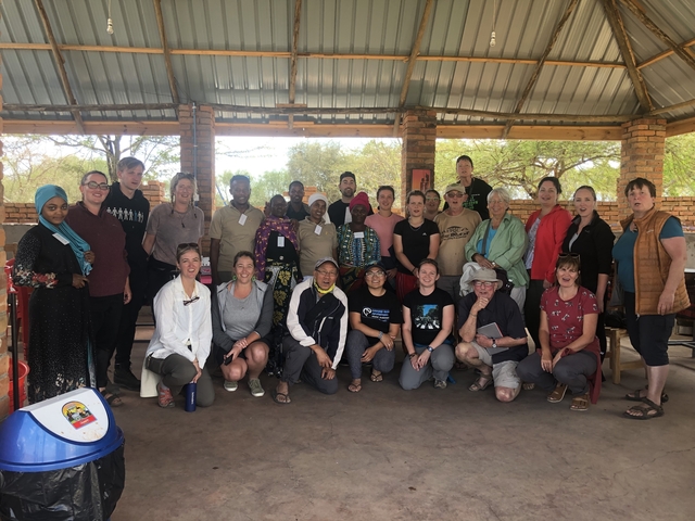 A large group posing inside a rustic building.