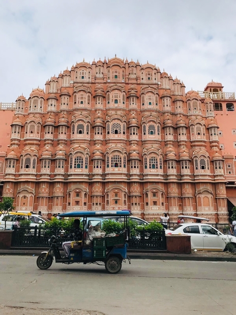       Intricate facade of the Hawa Mahal with lively street scene below.
  