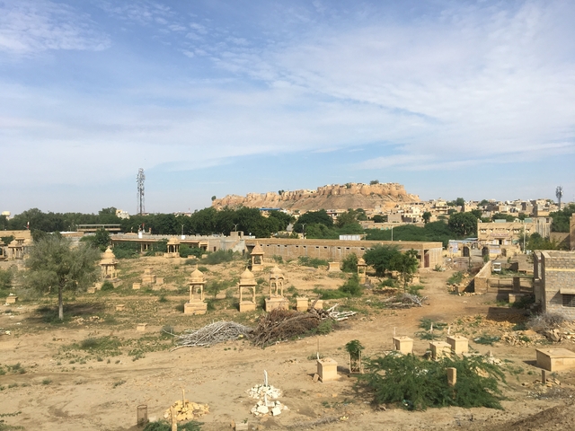       Expansive landscape with scattered structures and a distant fort on a hill.
  