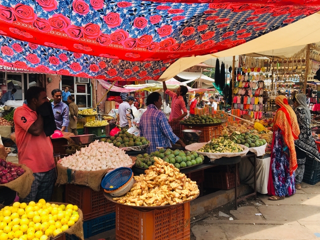       Bustling market scene with colorful fruits, vegetables, and vendors.
  