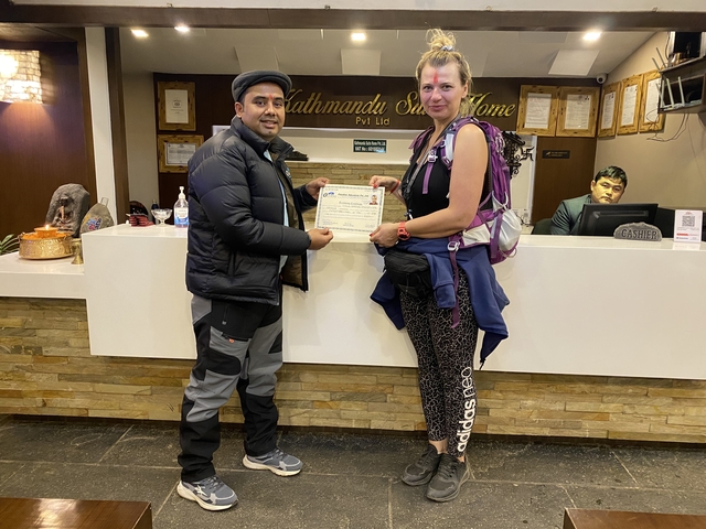 Two people holding a certificate in an indoor setting