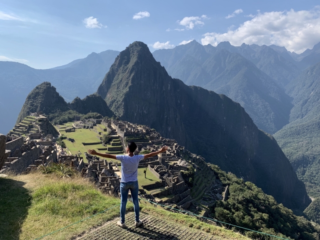       Person with arms outstretched enjoying the view of Machu Picchu.
  
