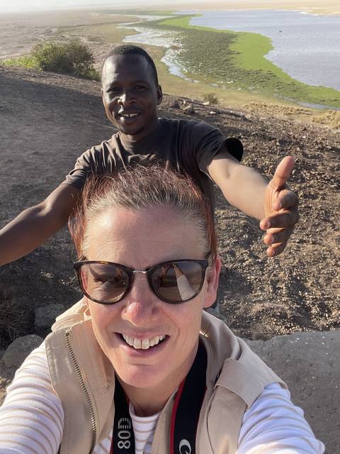       Two people smiling and posing with a natural background.
  