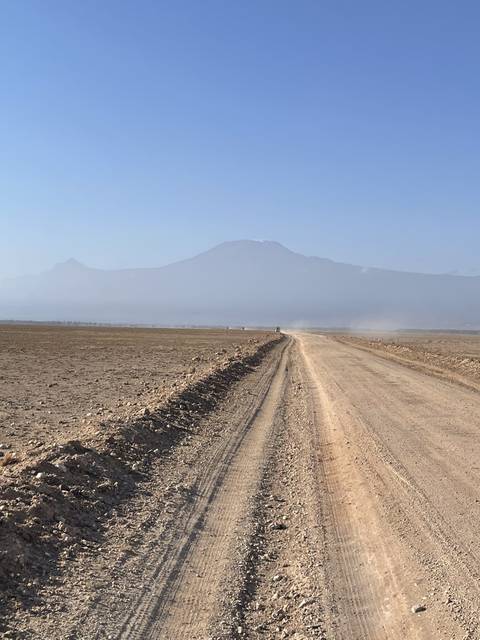 Dirt road extending towards a horizon with distant hills.