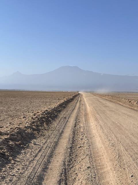       Dirt road extending towards a horizon with distant hills.
  