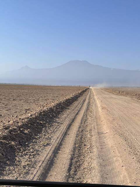      Dirt road extending towards a horizon with distant hills.
  