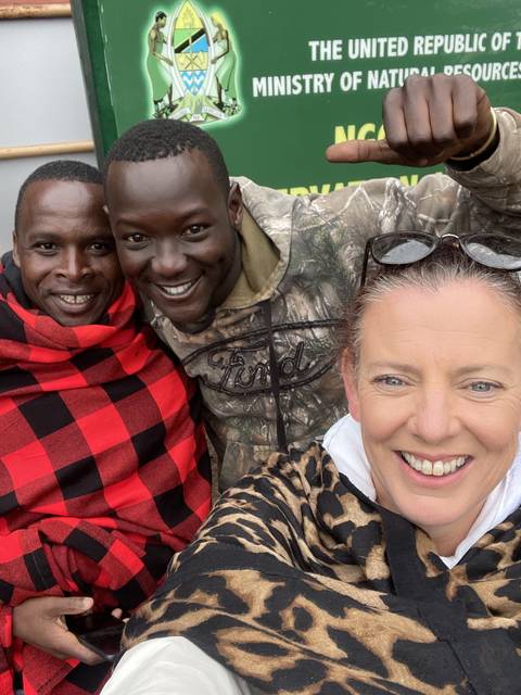       Three people posing in front of a sign from a Ministry.
  