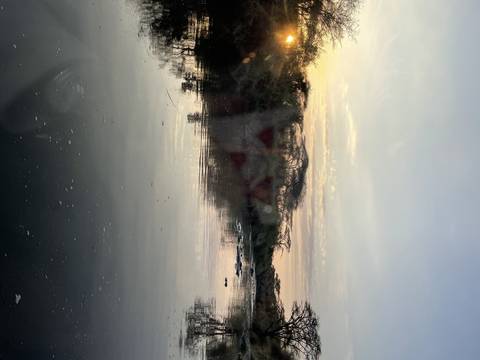       Sunset over a calm water body with reflections.
  