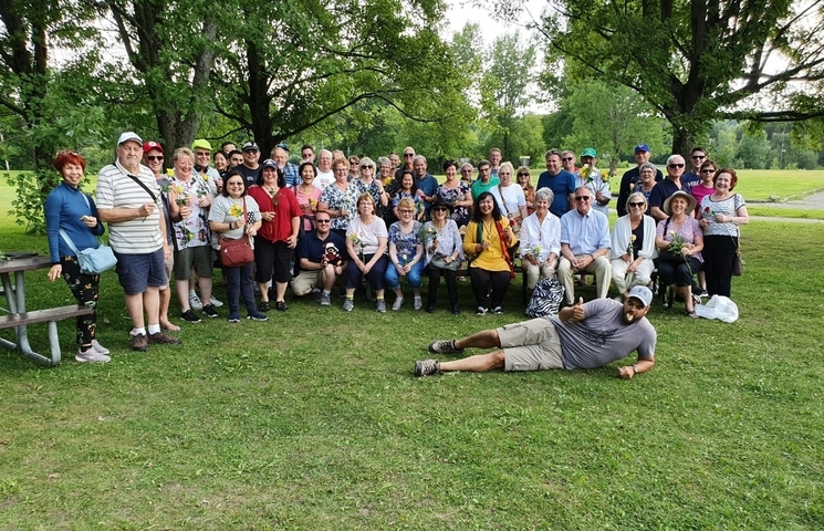 Large group photo in a park setting with trees and grass.