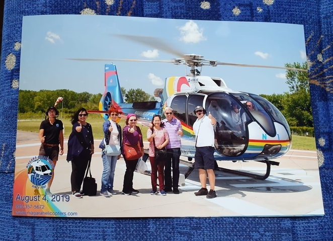 Group of people posing with a tour helicopter in the background.