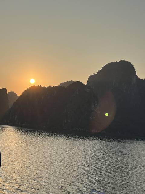 Sunset over water with silhouetted land formations.