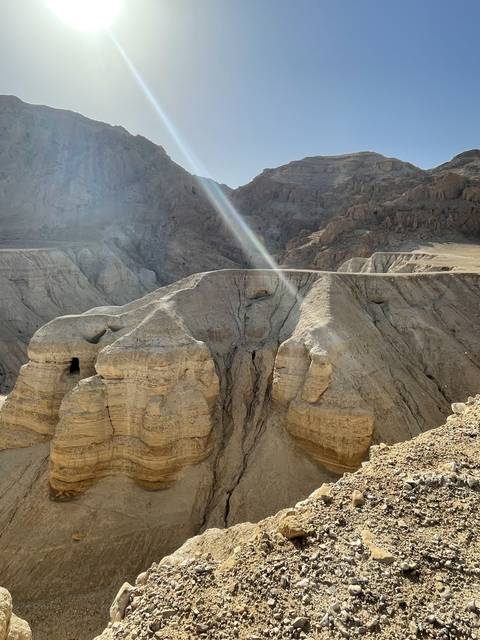 Rocky cliffs with a sun flare in a desert landscape.