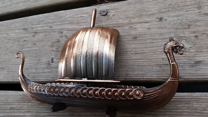       Model of a Viking ship displayed on a wooden surface.
  