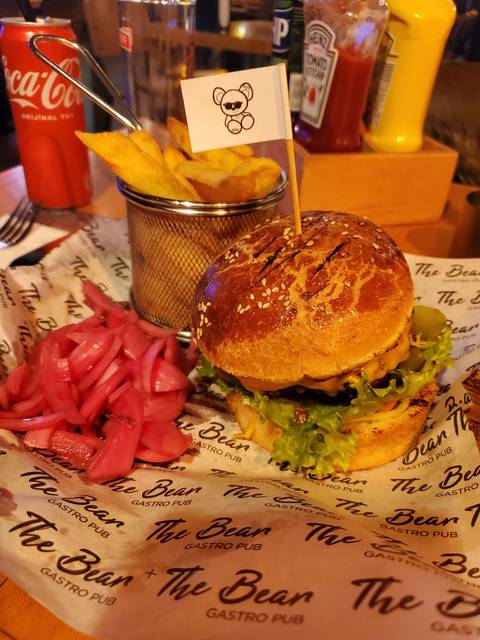       Burger with fries and pickles on a tray in a food setting.
  