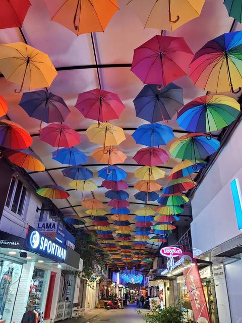       Colorful umbrellas hanging overhead in a market.
  