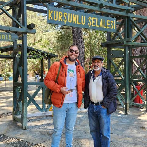       Two men standing at Kurşunlu Waterfall sign.
  