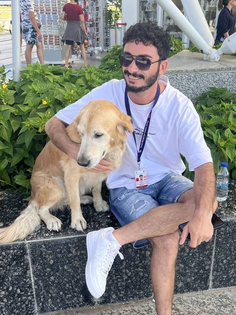       Man sitting with a dog on a sidewalk.
  