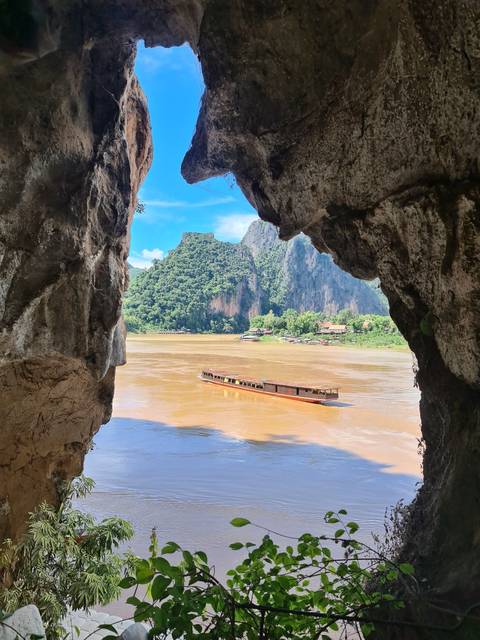       Scenic view of a boat on a river through a rock opening.
  