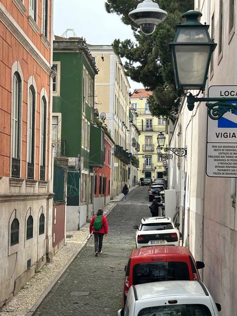 A narrow street with colorful buildings and parked cars.