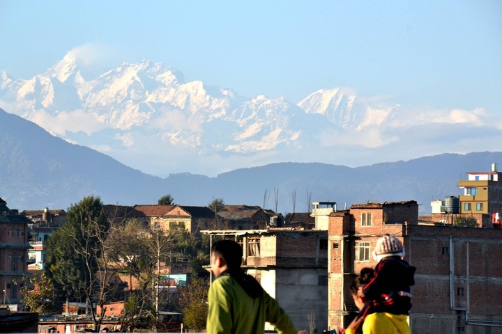 Cityscape with distant mountains, accompanied by a person.