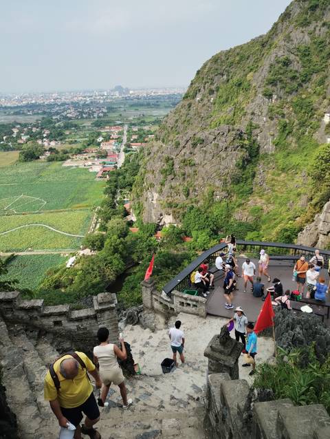 A view from a mountain with visitors and a scenic village below.
