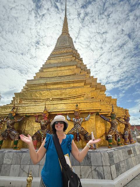       A woman posing happily with a golden temple.
  