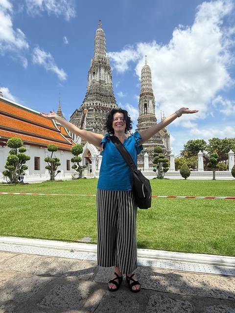       A woman posing in front of pagodas in a garden.
  