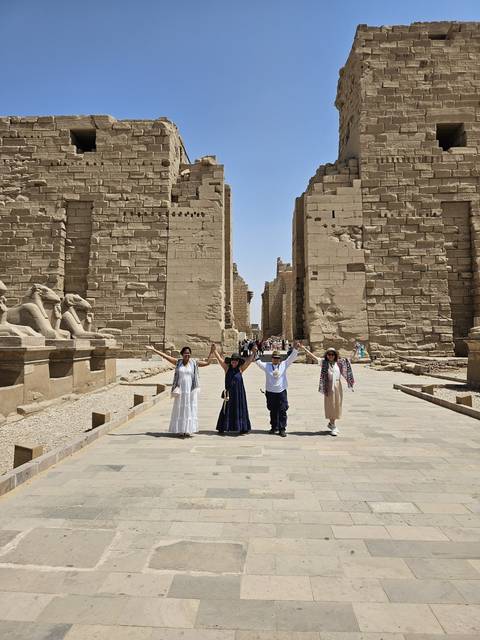 Four people posing in front of ancient stone ruins.